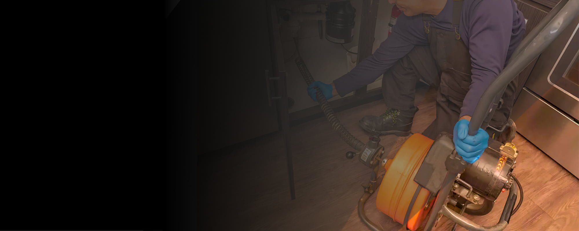 Plumber using sewer cable machine on drain.